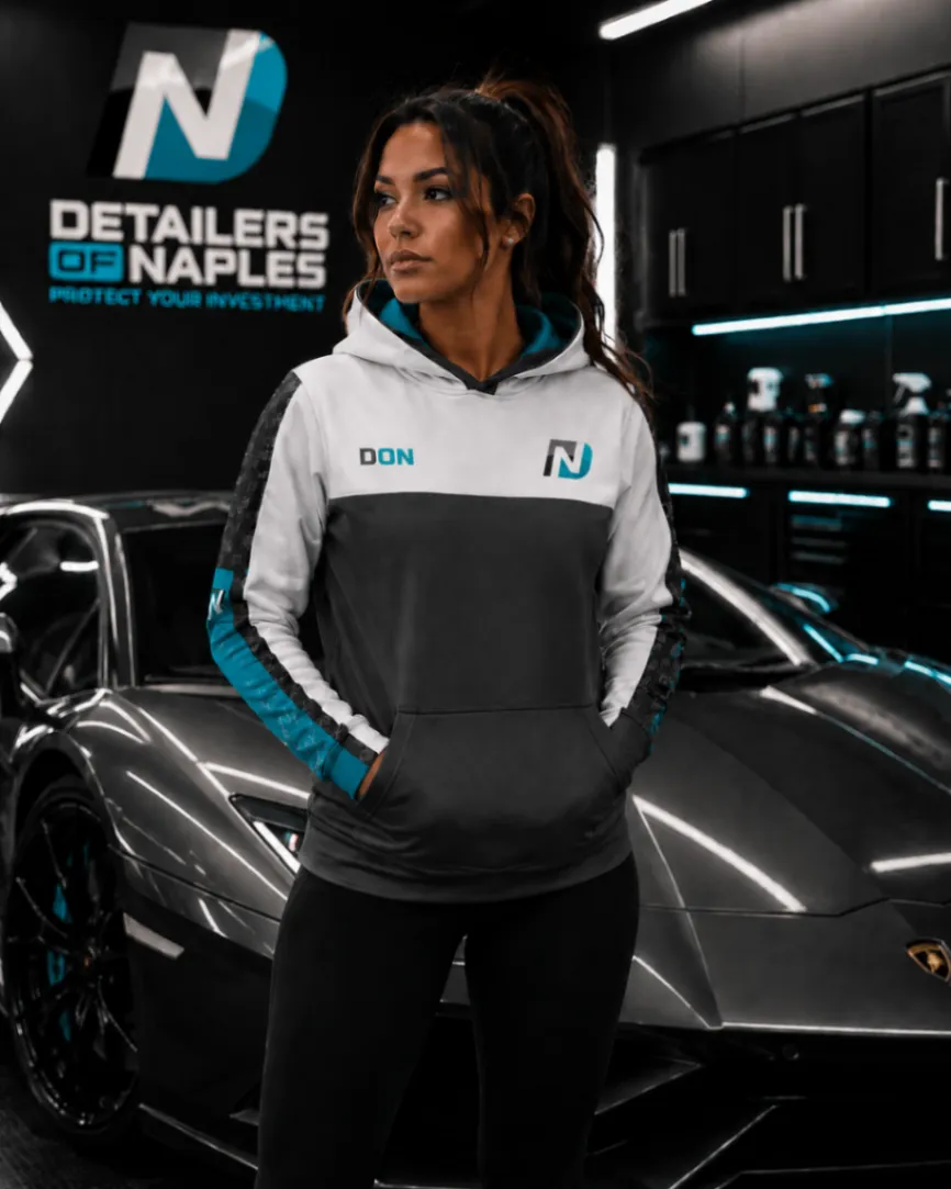 Woman wearing a custom hoodie beside a sports car